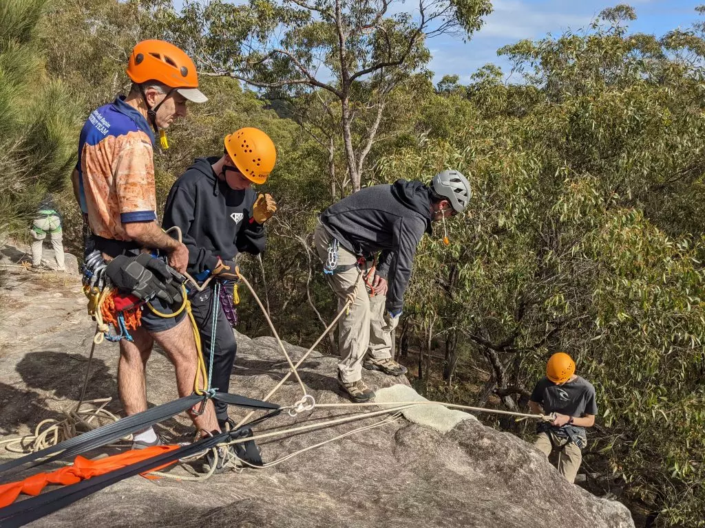 A Venturer Operates a top belay supervised by an Abseil Guide, whilst another Venturer is Abseiling at a Basic Rockcraft Abseil Course.
